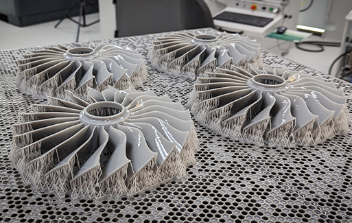 Four 3D printed fan blades sitting on honeycomb print bed