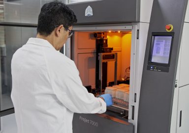 Man removing 3D printed parts from large industrial 3D printer