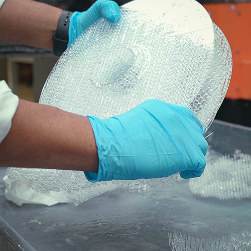 Person with blue gloves trimming 3D Print Supports for round part