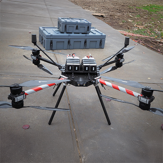 Large drone sitting on concrete with grey tubs in background